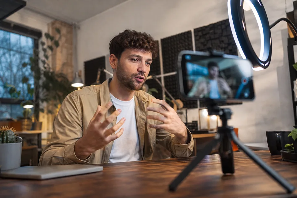 Creator filming a talking video on a phone tripod under a ring light in a home studio