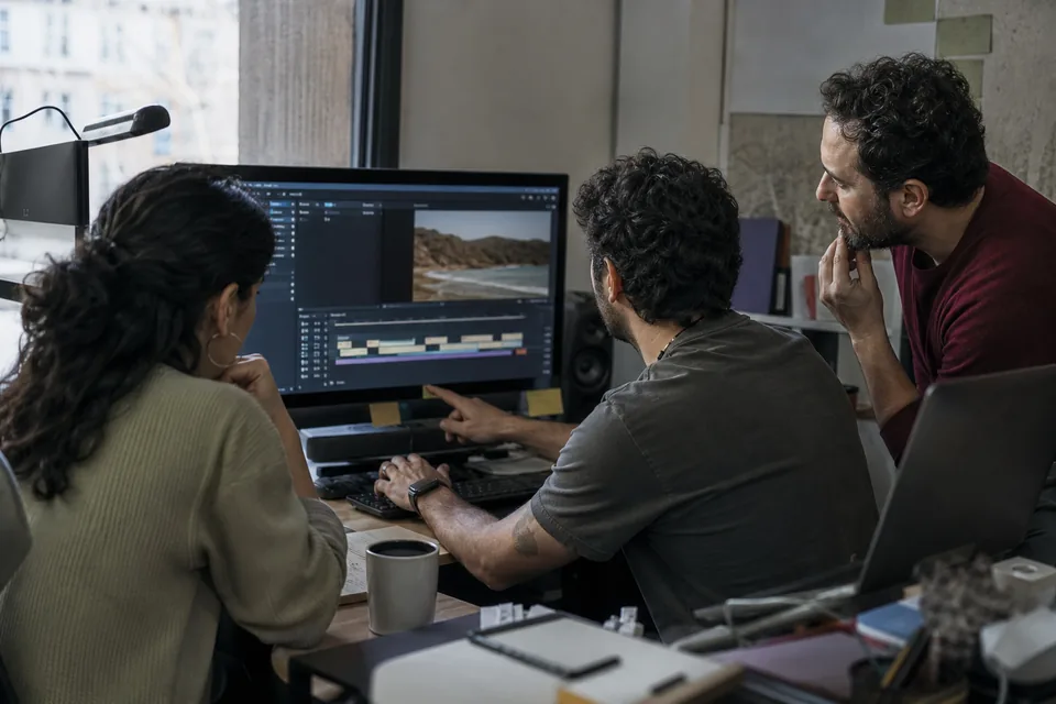 Three person social media team editing a subtitled video together on one monitor